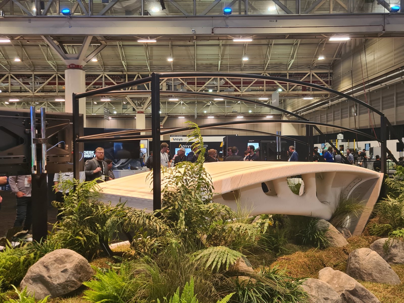 The completed bridge installed in a landscaped exhibition set with plants and rocks