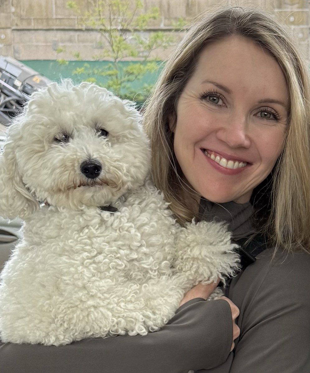 Stefanie Pender smiling, holding a small white curly-haired dog